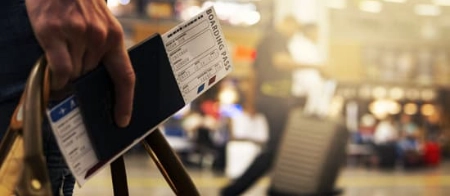 Person holding boarding pass and luggage at airport.